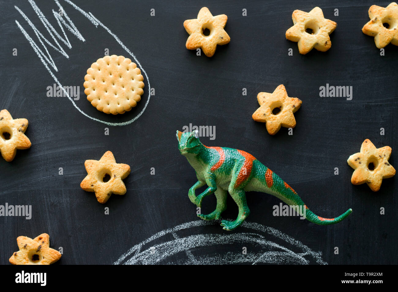 Dinosauro di plastica e cookie sulla lavagna, giocare e imparare con i bambini, dinosauri estinti a causa di un meteorite concept Foto Stock