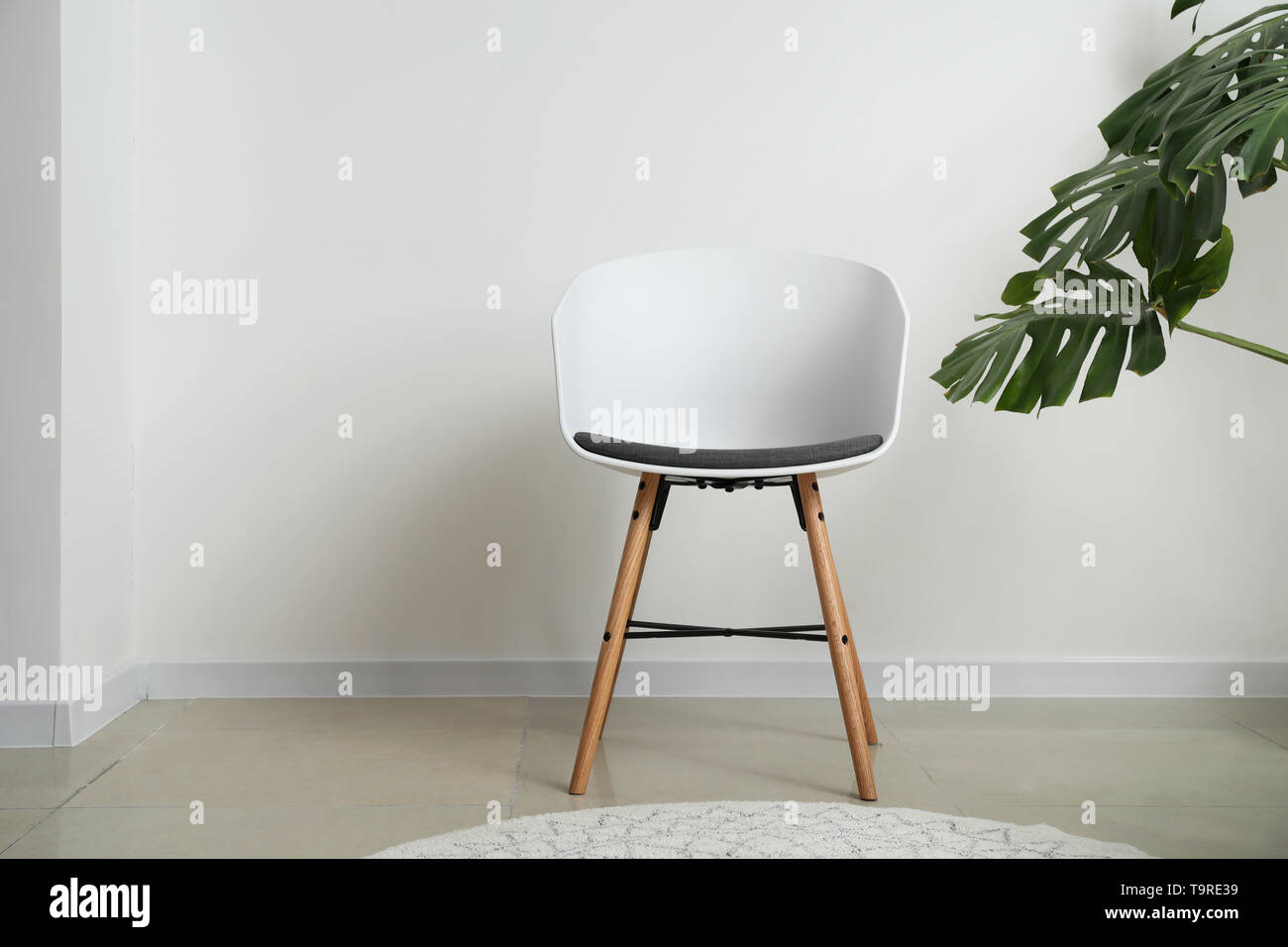 Sedia bianca con verde tropicale, lascia in camera di luce Foto Stock