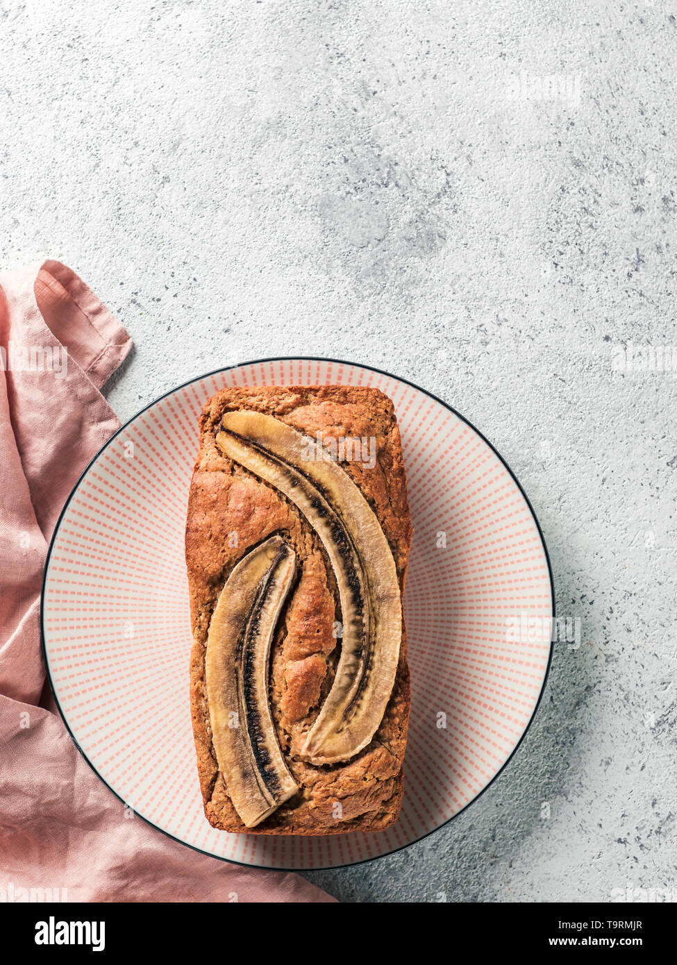 Il burro-libera,senza zucchero pane alla banana con farina di avena,soft ricotta,miele.vista superiore della piena pane alla banana sulla piastra rosa su sfondo grigio.spazio copia.idee ricetta per dieta sana prima colazione.Vertical Foto Stock