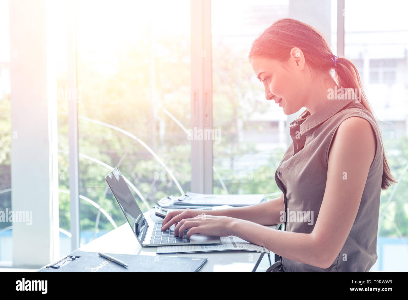 Ragazza lavoro digitando su laptop computer business in ufficio portait windows vista laterale Foto Stock