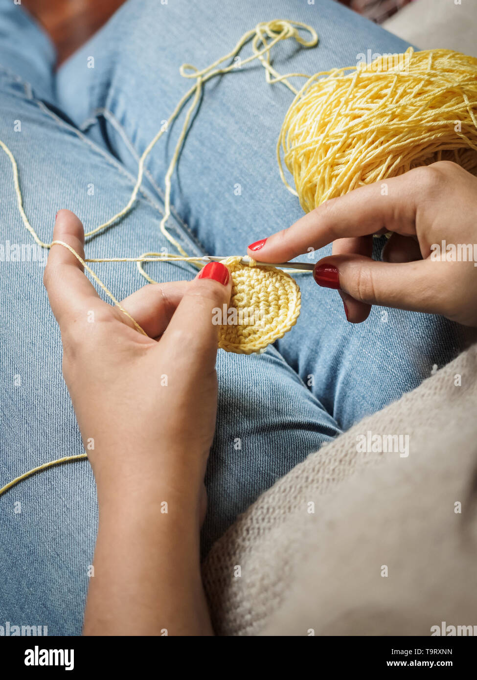 Ragazza crochet facendo con filo giallo e unghie dipinte di rosso, vicino a fotografare Foto Stock
