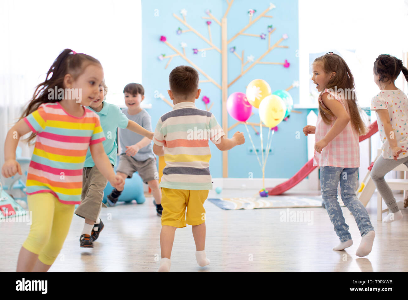 Infanzia, il tempo libero e il concetto di popolo - gruppo di bambini felici giocando Tag gioco e in esecuzione in ambienti interni Foto Stock