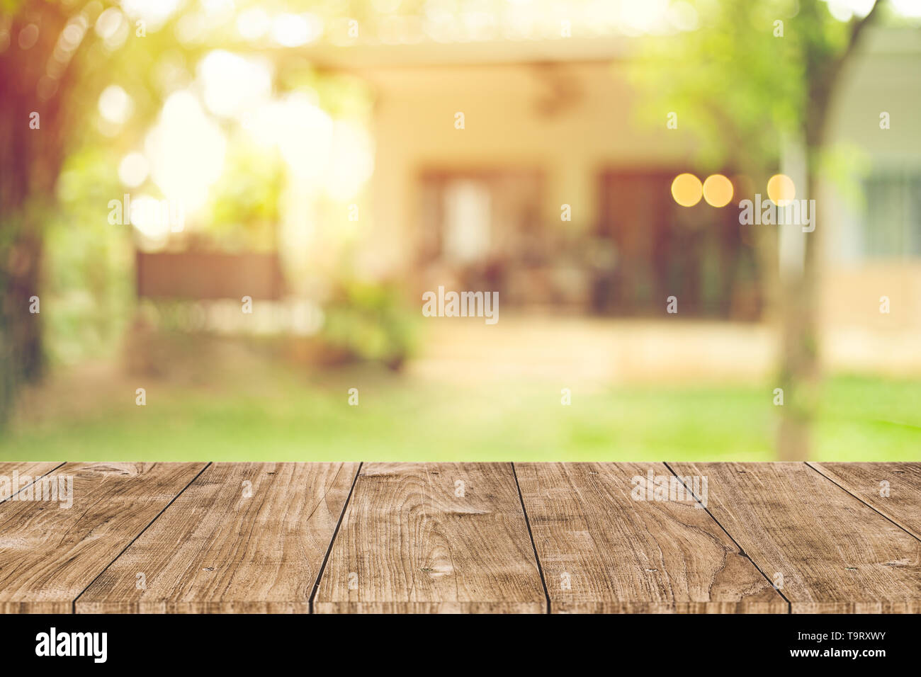 Tavolo in legno spazio verde con casa vista cortile blur sullo sfondo per modello per pubblicità Foto Stock