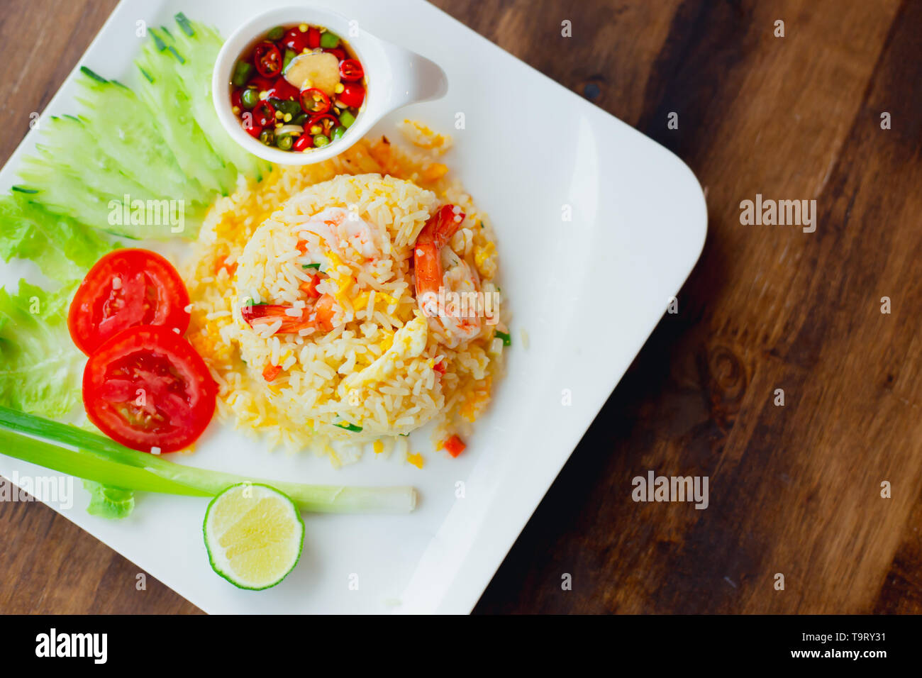 Stile Thailandese Gamberi fritti ricetta riso top view servita su un tavolo di legno con decorazione vegetale sul piatto bianco Foto Stock