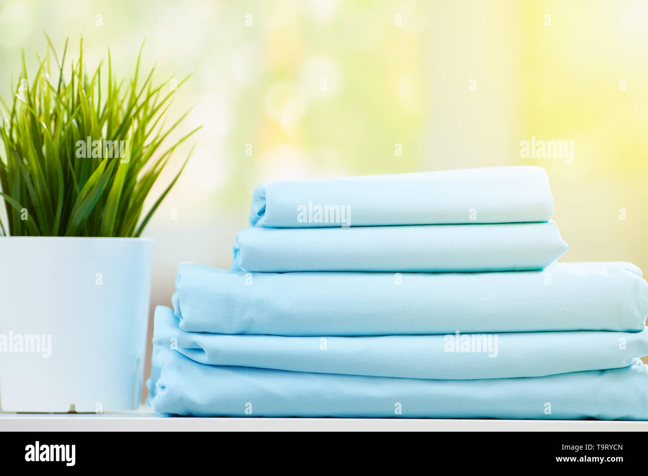 Closeup pila di blu biancheria da letto pulita su sfondo sfocato. Foto Stock