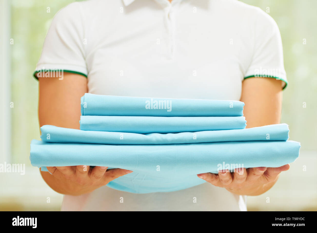 Una donna può contenere una pila di pulire ripiegato biancheria blu. Sfondo sfocato. Close-up. Foto Stock