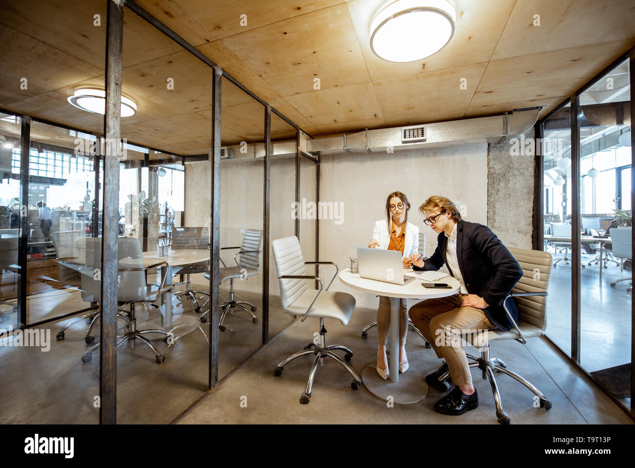 Business uomo e donna che lavorano nella sala riunioni, ampia vista interna sulla camera con partizioni trasparente Foto Stock