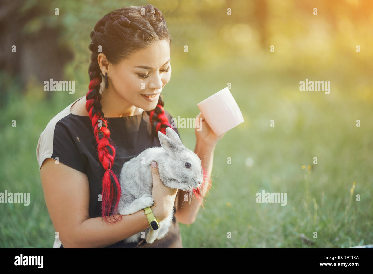 Bella ragazza con i capelli trecciatura Huggs un coniglio sulla bella Estate Natura Foto Stock