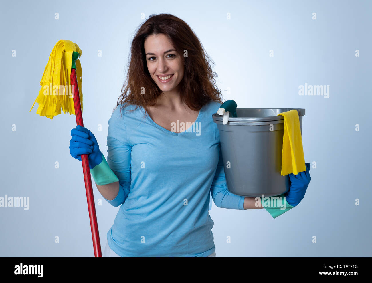 Bella felice donna casalinga azienda attrezzature per la pulizia. Orgogliosi delle donne, il servizio di pulizia professionale, cameriera e lavori di casa. Ritratto in studio isola Foto Stock