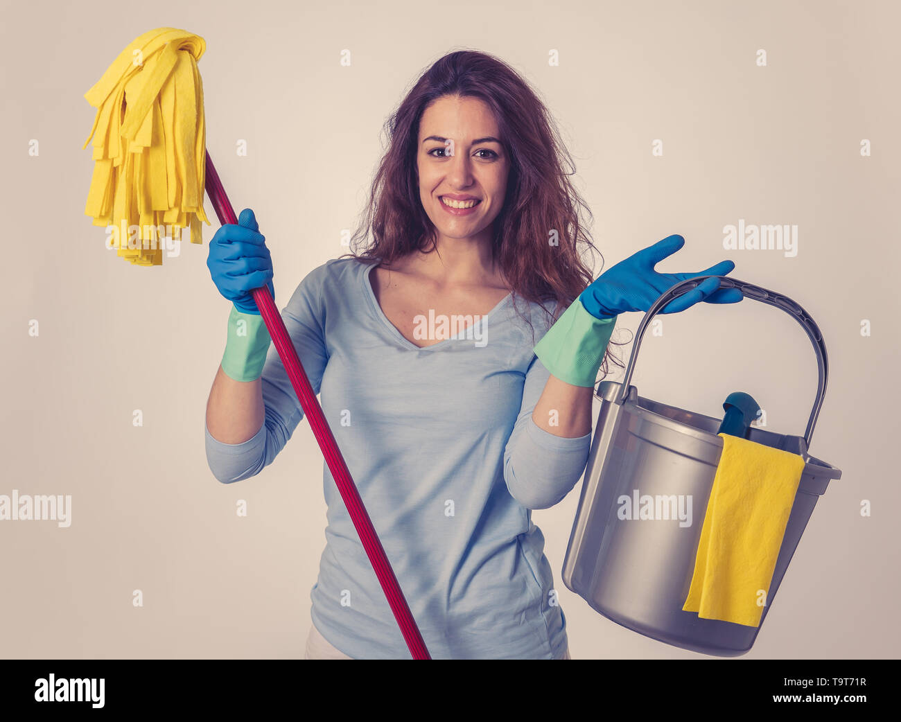 Bella felice donna casalinga azienda attrezzature per la pulizia. Orgogliosi delle donne, il servizio di pulizia professionale, cameriera e lavori di casa. Ritratto in studio isola Foto Stock