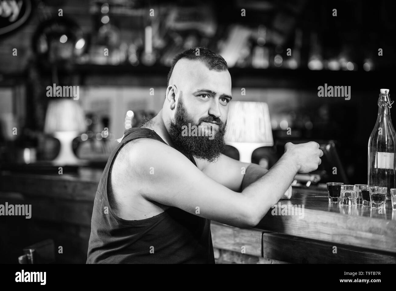 Guy trascorrere il tempo libero nel bar con alcolici. L'uomo ubriaco sedersi da solo nel pub. L' alcolismo e depressione. L'alcol addicted concetto. Tanga uomo brutale bere al Foto Stock