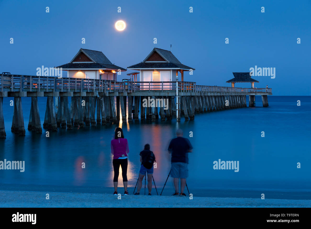 Fotografi catturare l'impostazione luna piena e la mattina presto twilight oltre il Molo di Napoli, Naples, Florida, Stati Uniti d'America Foto Stock