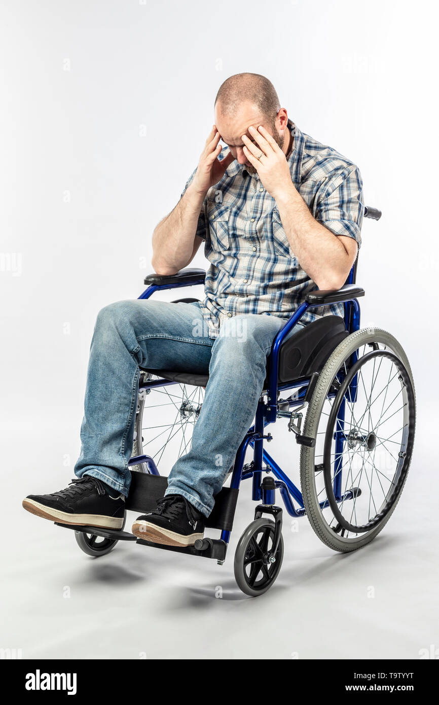 Disabilitato l'uomo in una disperata e triste sedia a rotelle con la testa tra le mani. Concetto di difficoltà e di rassegnazione. Foto Stock
