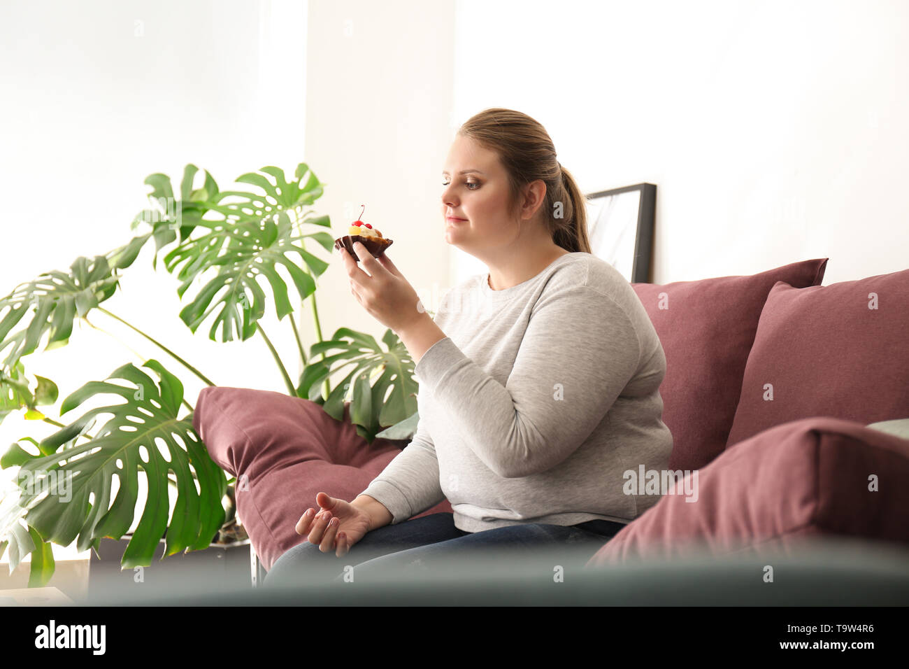 Bella dimensione plus ragazza con torta dolce a casa. Concetto di positività del corpo Foto Stock