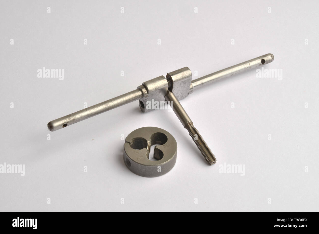 Un filo di metallo il taglio tocca detenute in un apprendista di fatto a mano tocca titolare, con una filettatura fustella accanto ad esso. Foto Stock