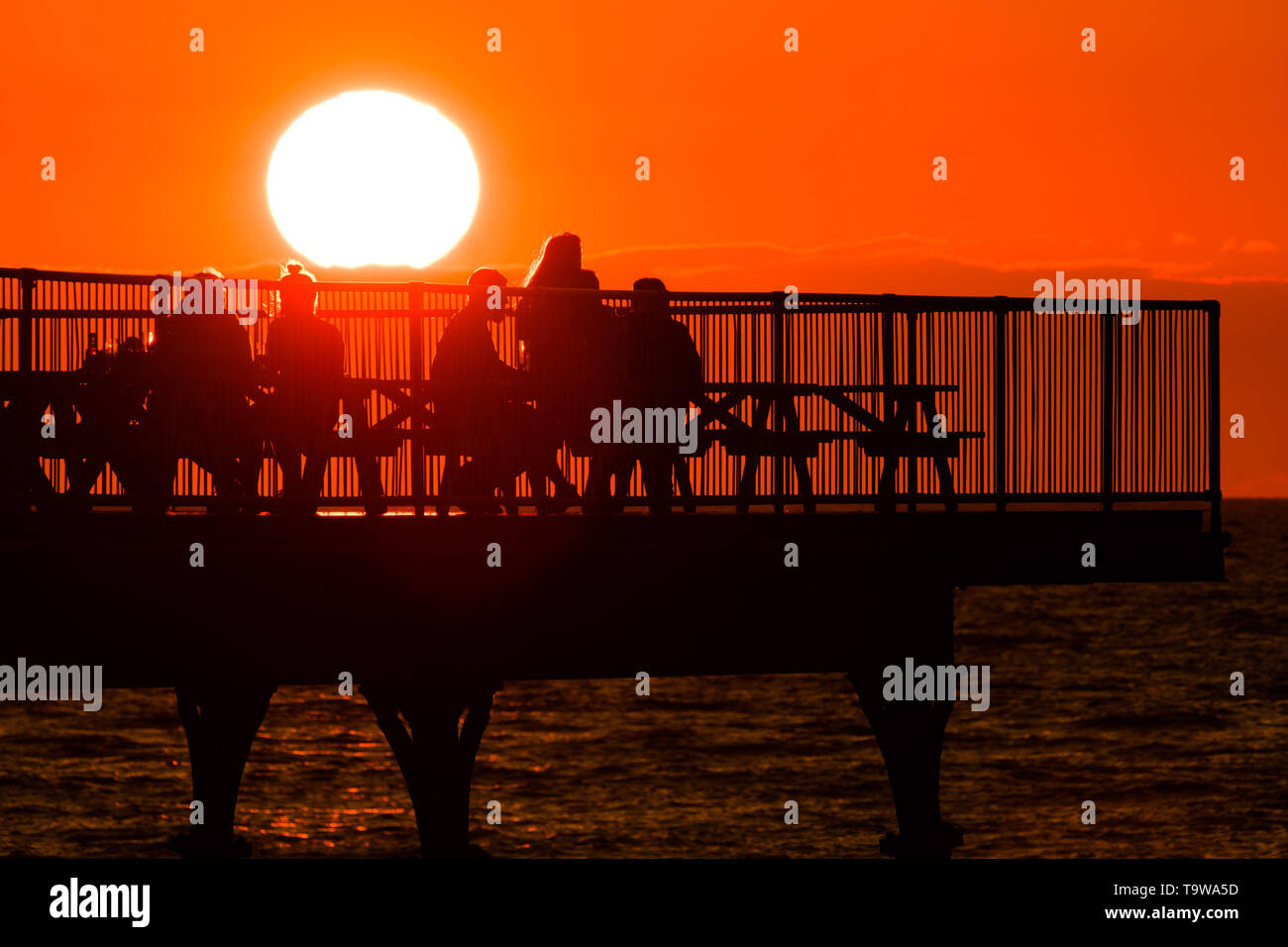 Aberystwyth Wales UK, lunedì 20 maggio 2019 UK Meteo: la gente sul molo di godersi un drink e la vista della gloriosa Golden Sunset over Cardigan Bay, alla fine di una giornata di caldo sole primaverile in Aberystwyth Wales. Il tempo è buono per i prossimi giorni , con extended magie del caldo sole Photo credit: Keith Morris / Alamy Live News Foto Stock