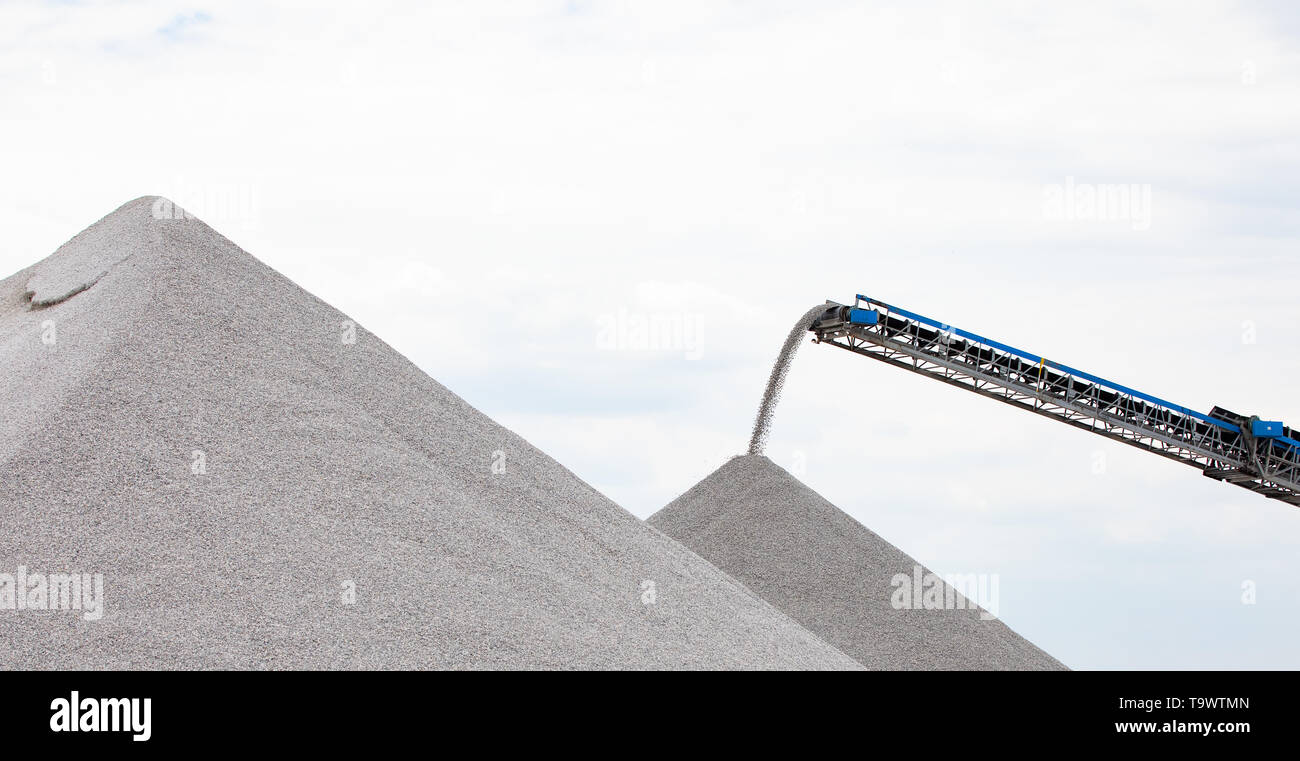 Industria nazionale internazionale spedizione trasportatore telescopico di movimento del nastro di materiale di roccia su un riverfront itinerario di spedizione Foto Stock