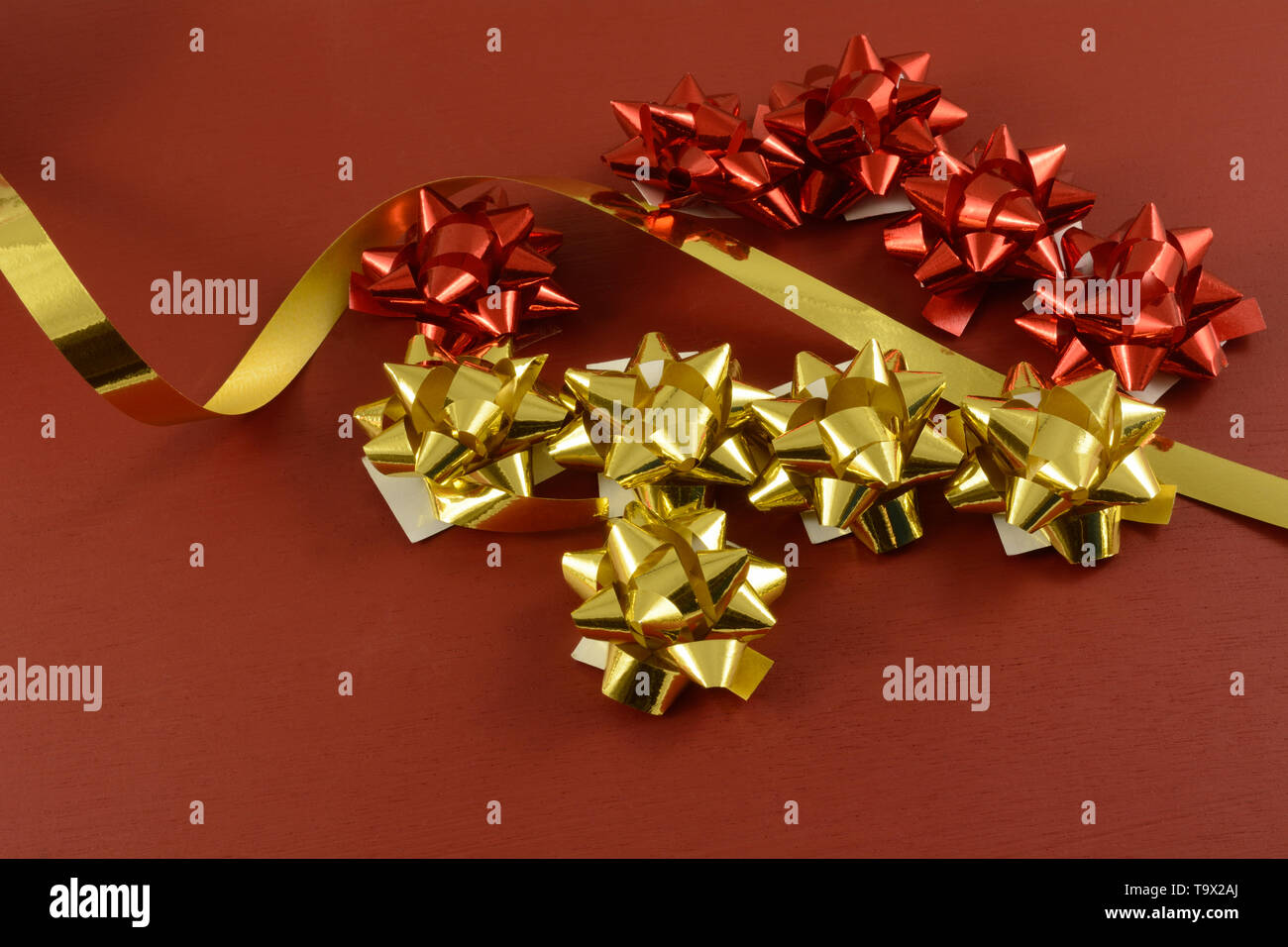 Rosso e oro fiocchi di Natale e dono stuprato nastro su sfondo rosso Foto Stock