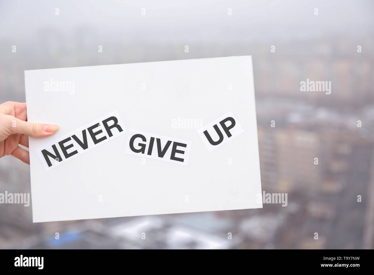 Femmina di mano che trattiene il foglio di carta con il testo mai rinunciare all'esterno. Concetto di suicidio Foto Stock