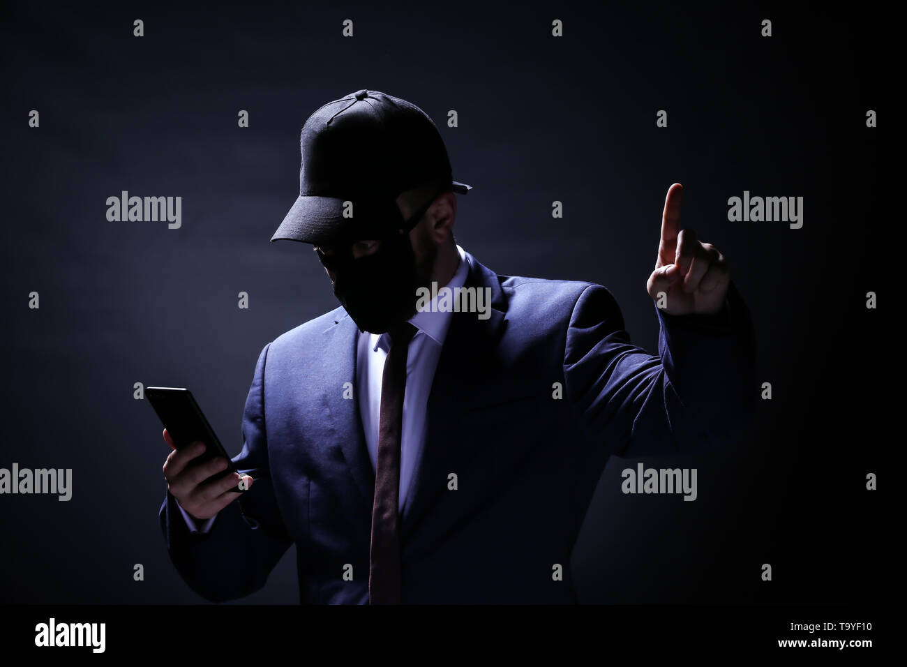 Professional hacker con il cellulare su sfondo scuro. Concetto di furto di internet Foto Stock