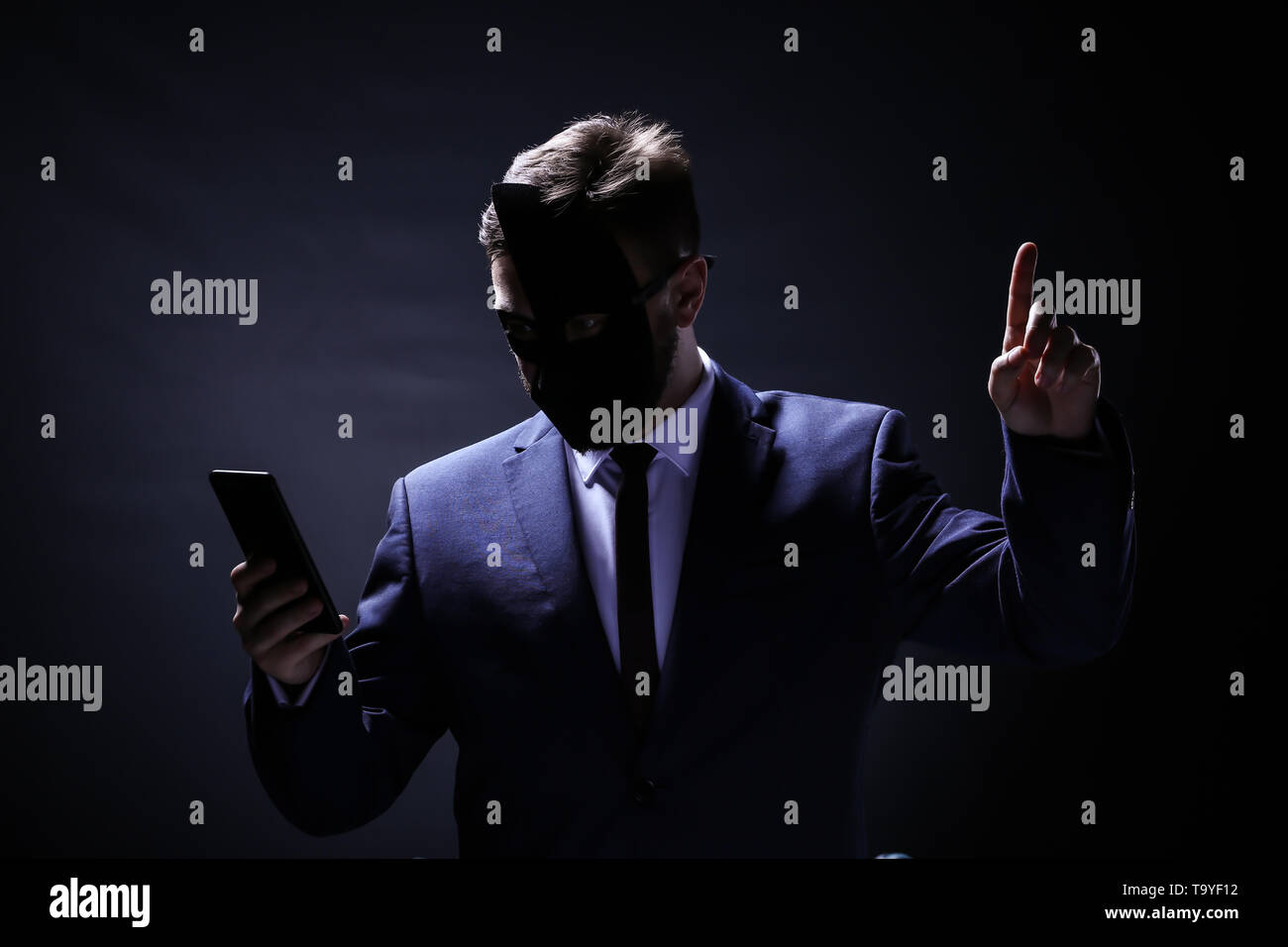 Professional hacker con il cellulare su sfondo scuro. Concetto di furto di internet Foto Stock