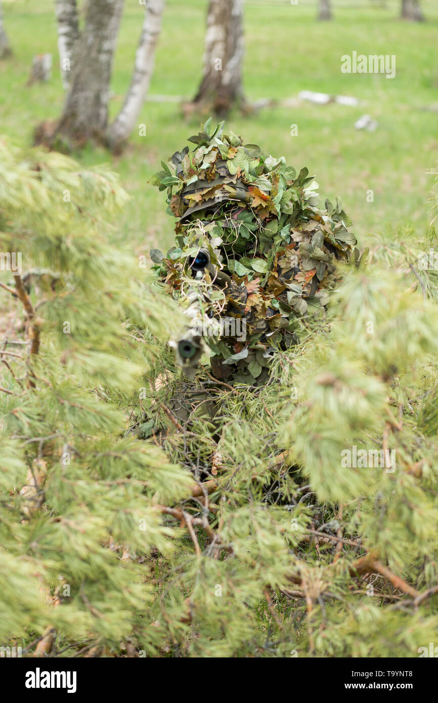 Primo piano del giovane soldato di mimetizzazione o azienda sniper rifle e  spara attraverso verdi alberi Foto stock - Alamy
