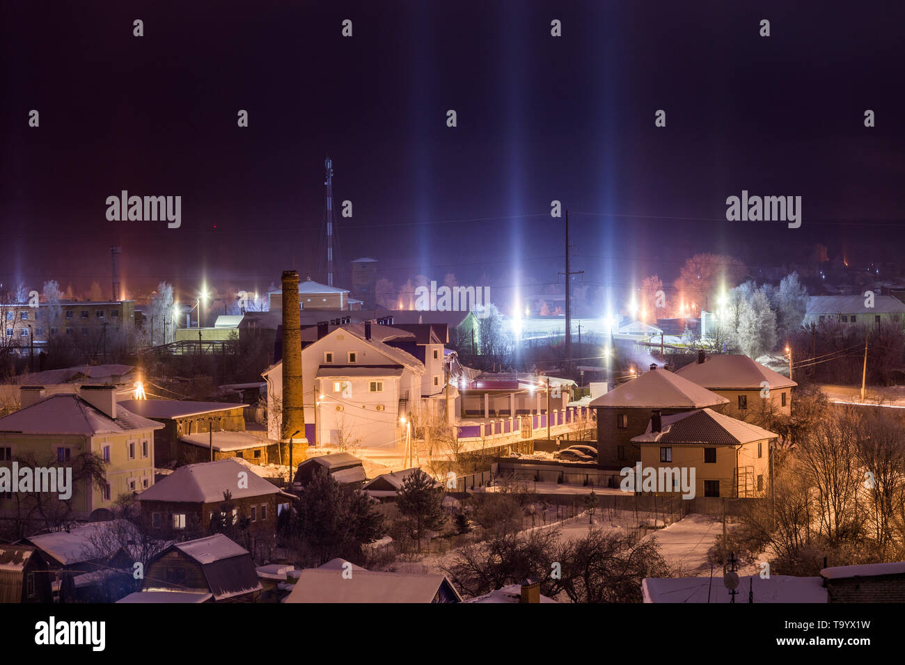 Notte paesaggio invernale con pilastri di luce fenomeno atmosferico. Foto Stock