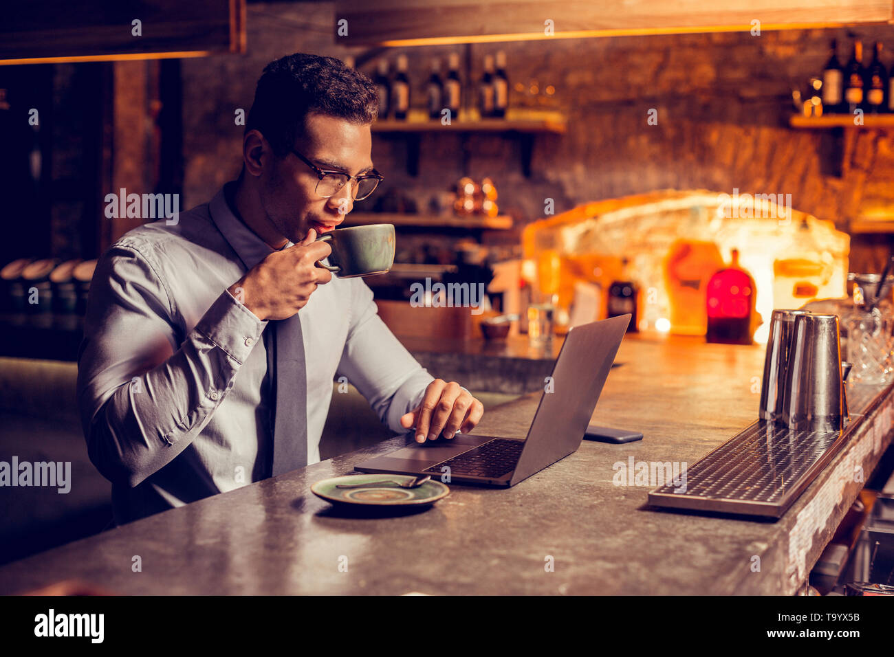 Imprenditore a bere un caffè mentre si lavora sul computer portatile Foto Stock