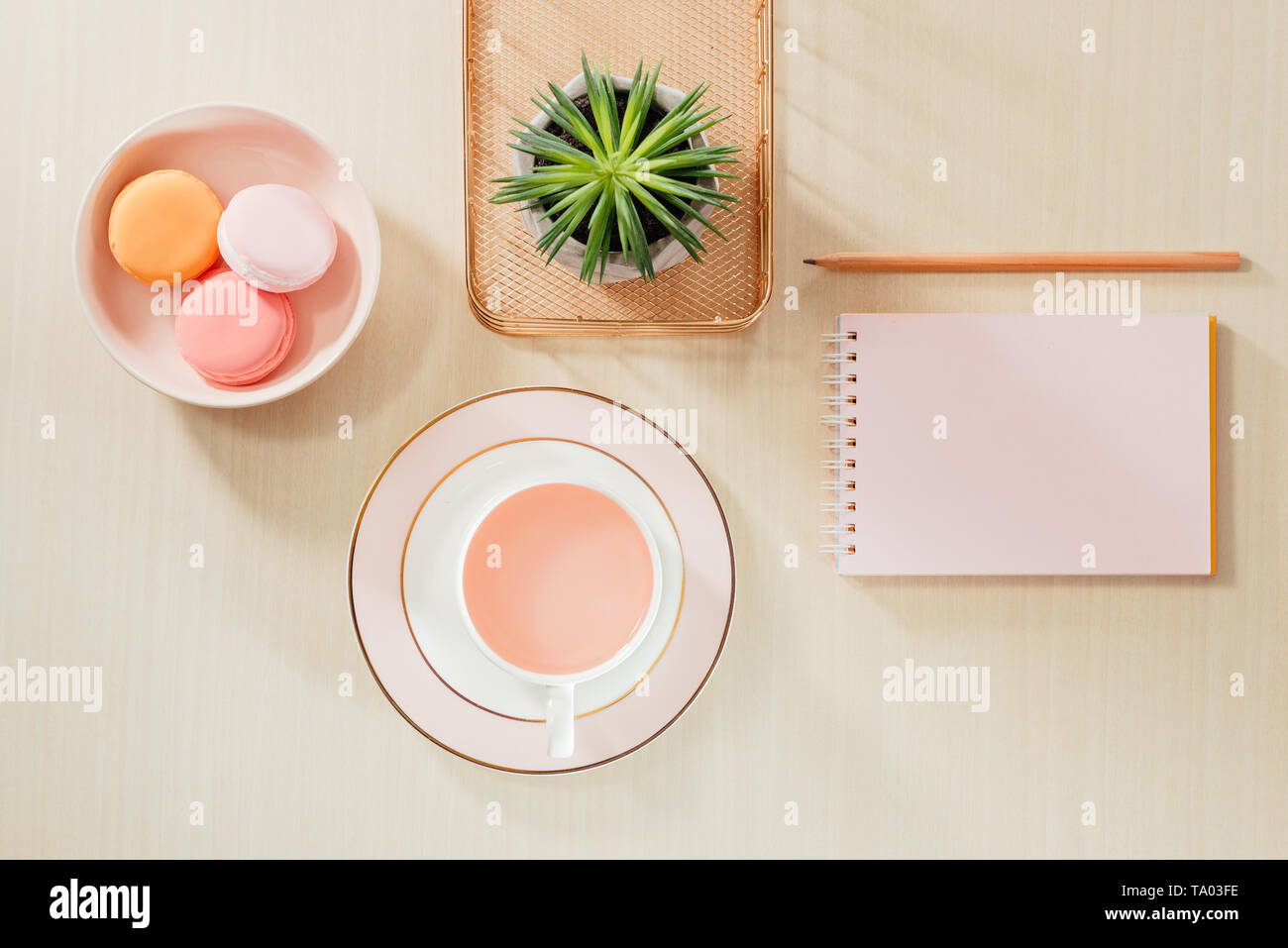 Nello stile di fotografia di stock ufficio beige scrivania con blank notebook, amaretti, forniture e tazza da caffè Foto Stock
