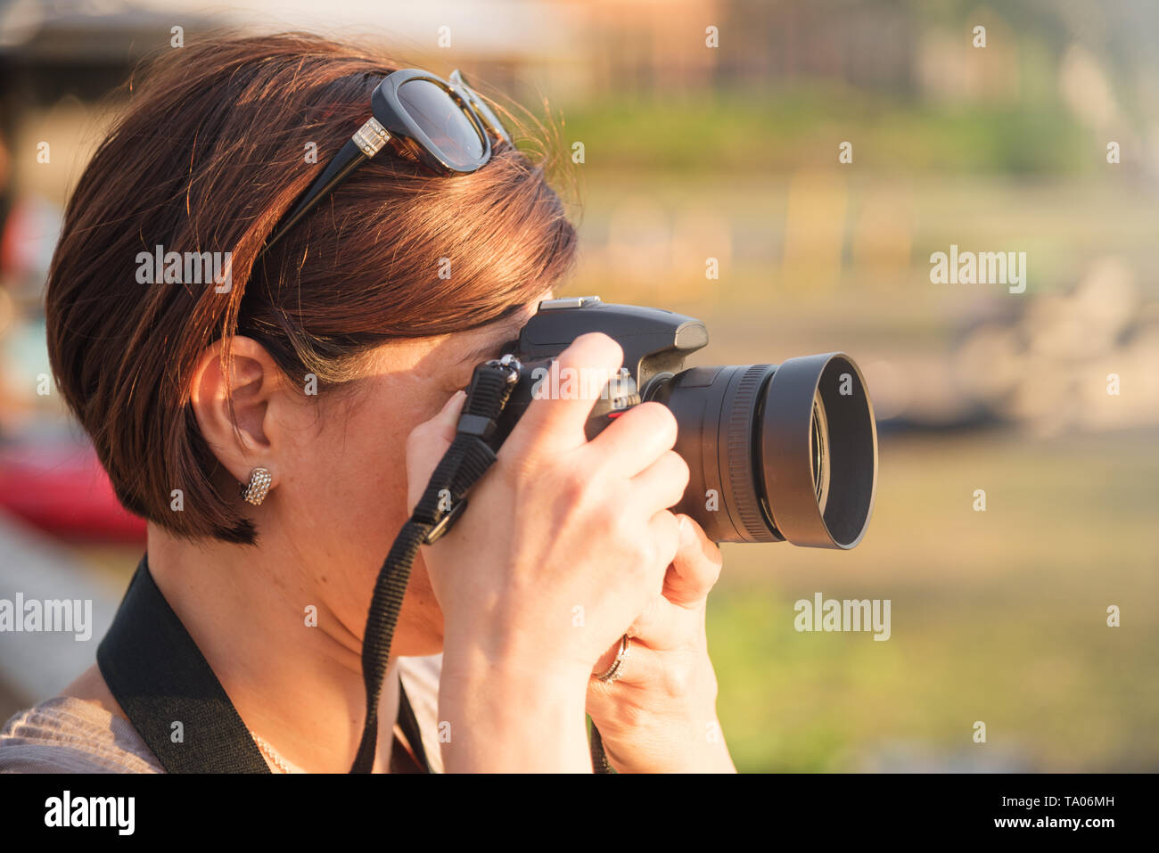 Donna fotografo professionista di scattare le foto con una fotocamera DSRL in un parco al tramonto. Foto Stock