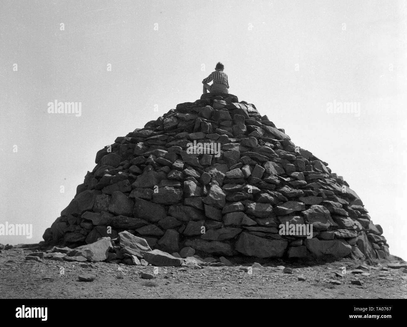 Un ragazzo si trova sulla cima di un gran mucchio di pietre c1955. Foto di Tony Henshaw Foto Stock