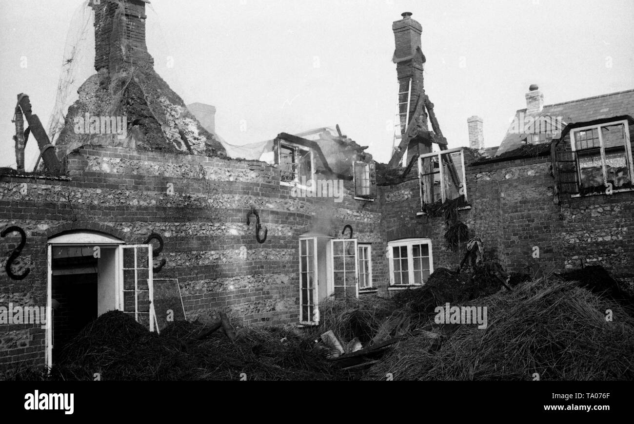 Recupero di beni a seguito di una casa di paglia fire c1973 in Weymouth Dorset, area. Nota la continuano a covare edificio come vigili del fuoco di fare ciò che rimane al sicuro. Foto di Tony Henshaw Foto Stock