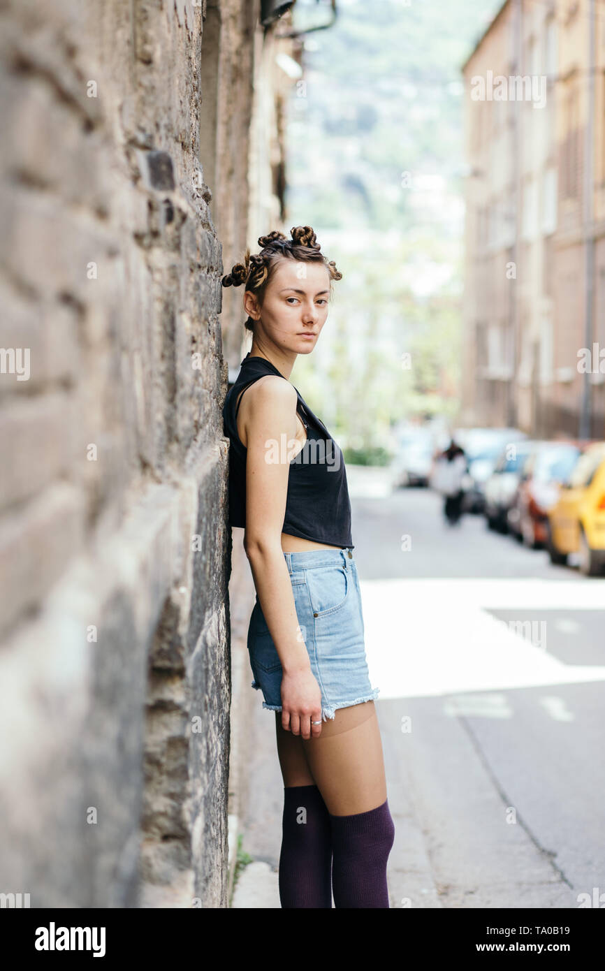 Moda ritratto di una giovane donna in piedi e appoggiata sulla parete edilizia Foto Stock
