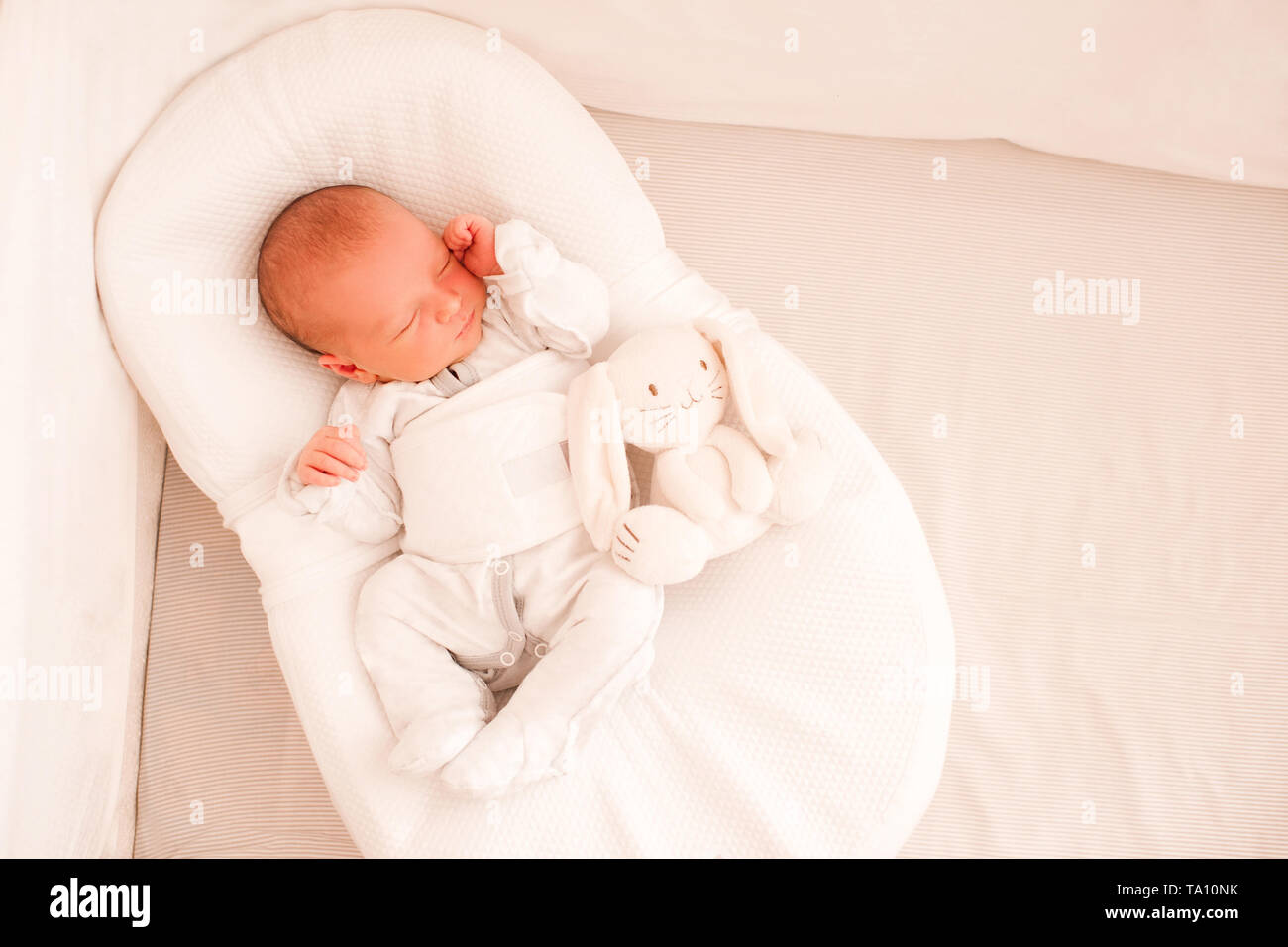 Neonato bambino dorme in cocoon indossando pigiami in primo piano letto. Buona mattina. Infanzia. Uno stile di vita sano. Foto Stock