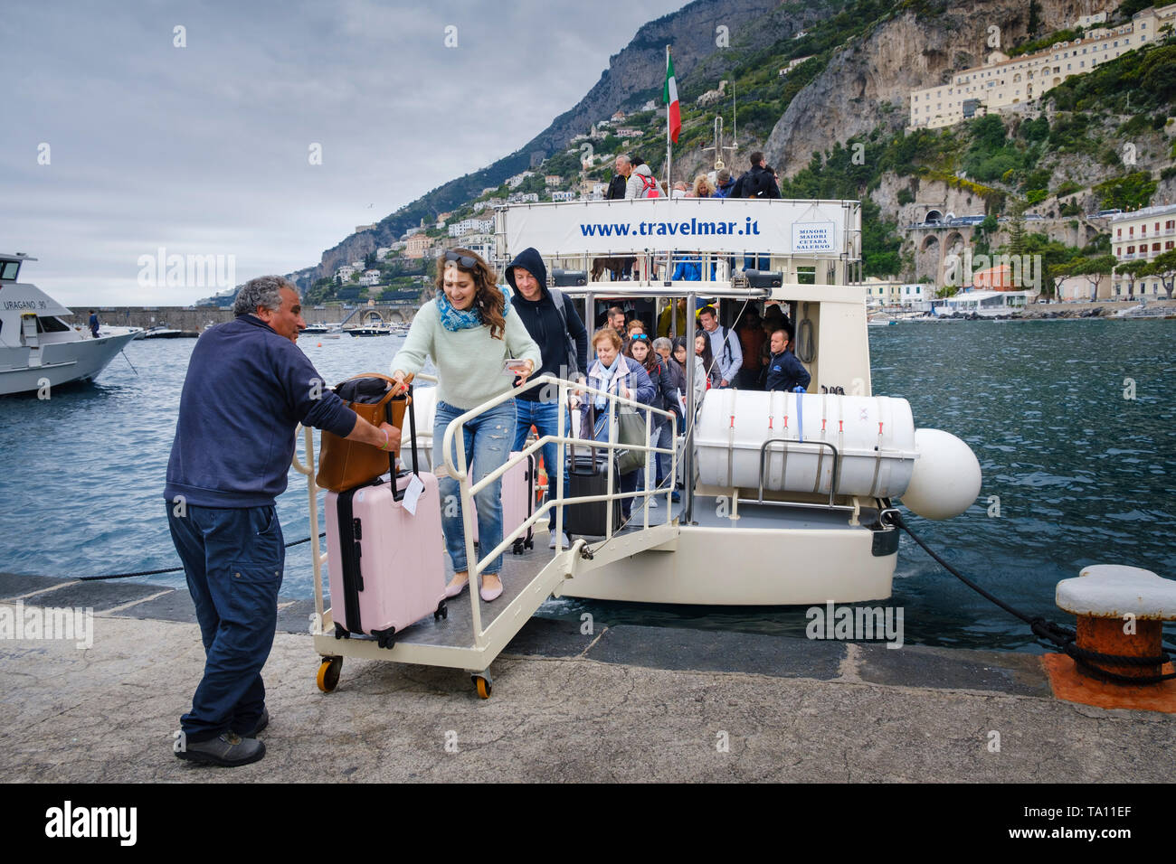 Trasporto in barca. Turista con i bagagli e gli altri passeggeri lo sbarco da un traghetto Travelmar presso il porto di Amalfi sulla Costiera Amalfitana. Foto Stock