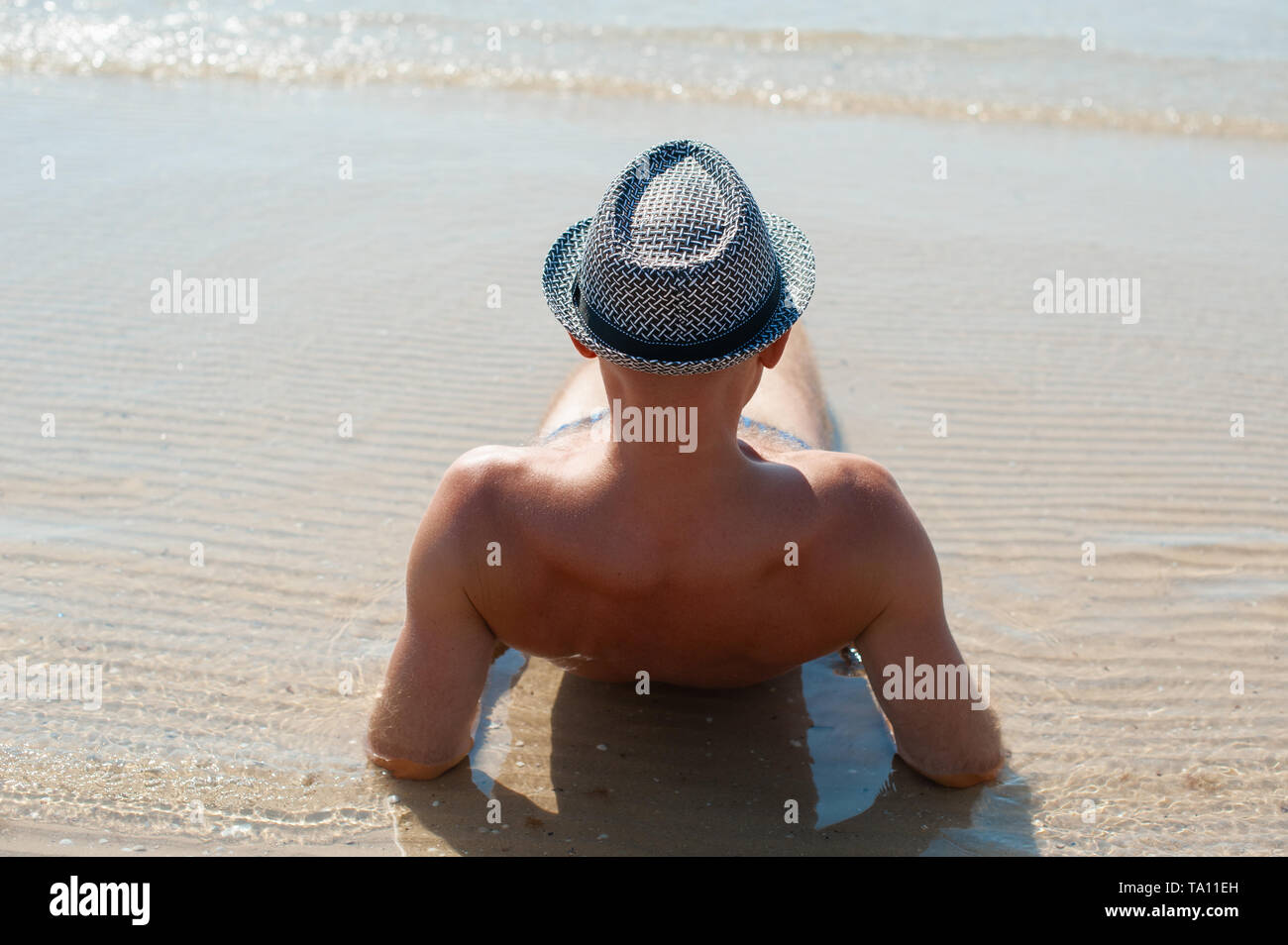 Elegante giovane maschio modello uomo disteso sulla spiaggia di sabbia di indossare hipster estate hat godendo di viaggio estivo vacanza vicino al mare Foto Stock