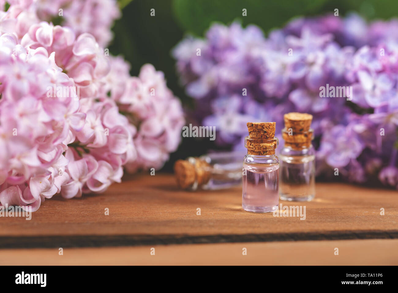 Olio essenziale di bottiglie e fiori lilla sul tavolo di legno Foto Stock