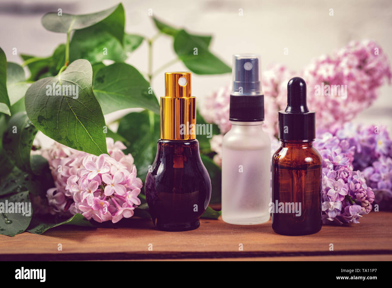 Profumo irroratrici e olio essenziale di bottiglie con fiori lilla Foto Stock