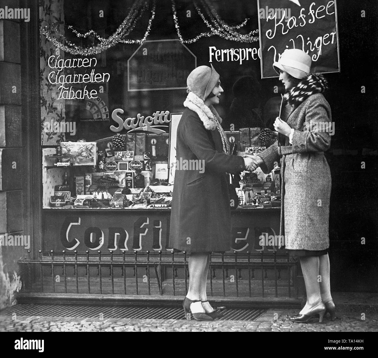 Conversazione tra due donne di fronte a mom-e-pop shop. Foto Stock