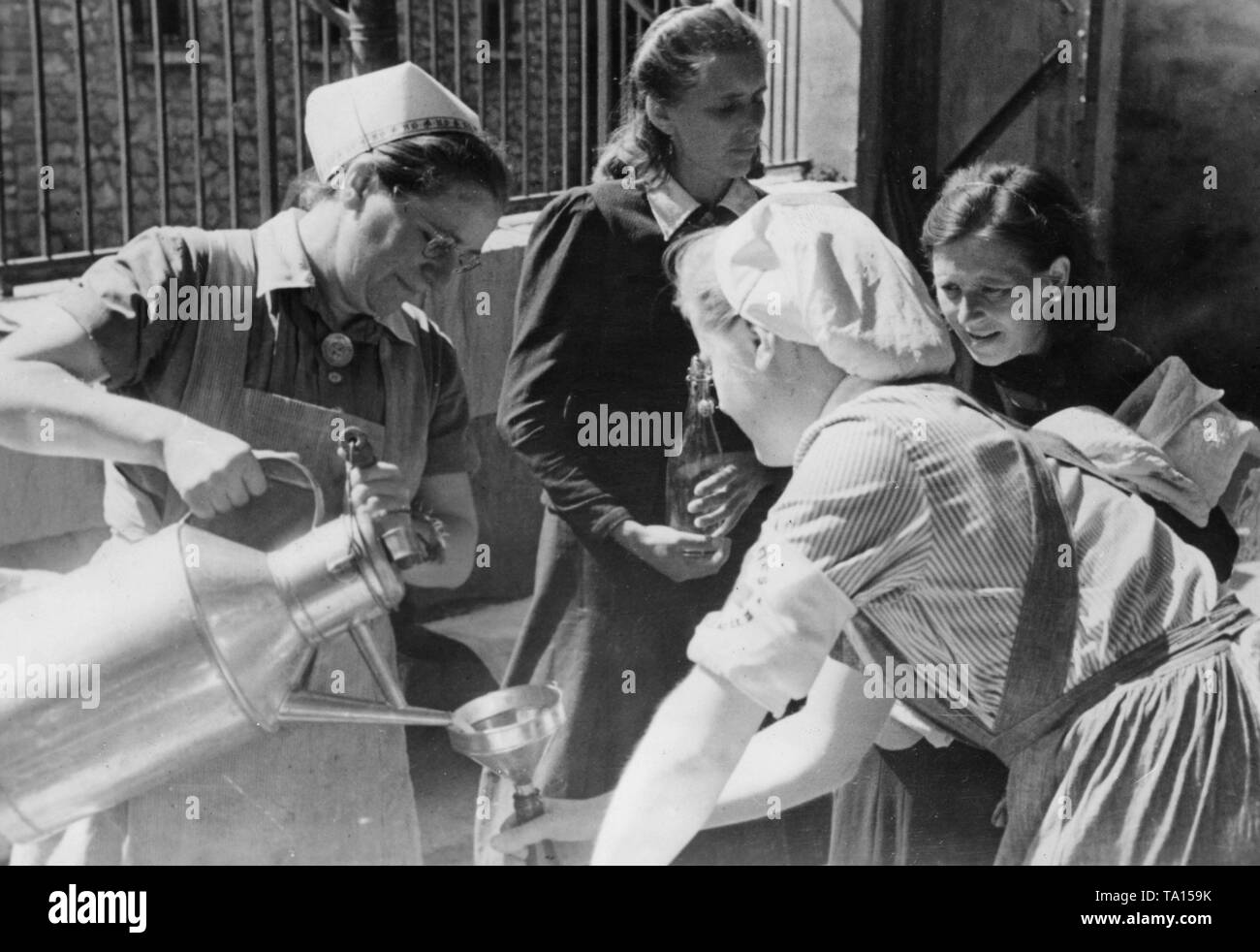 Gli infermieri del NS Volkswohlfahrt dare il latte alle famiglie che erano in francese inumazione camps. Reporter di guerra: Weber. Foto Stock