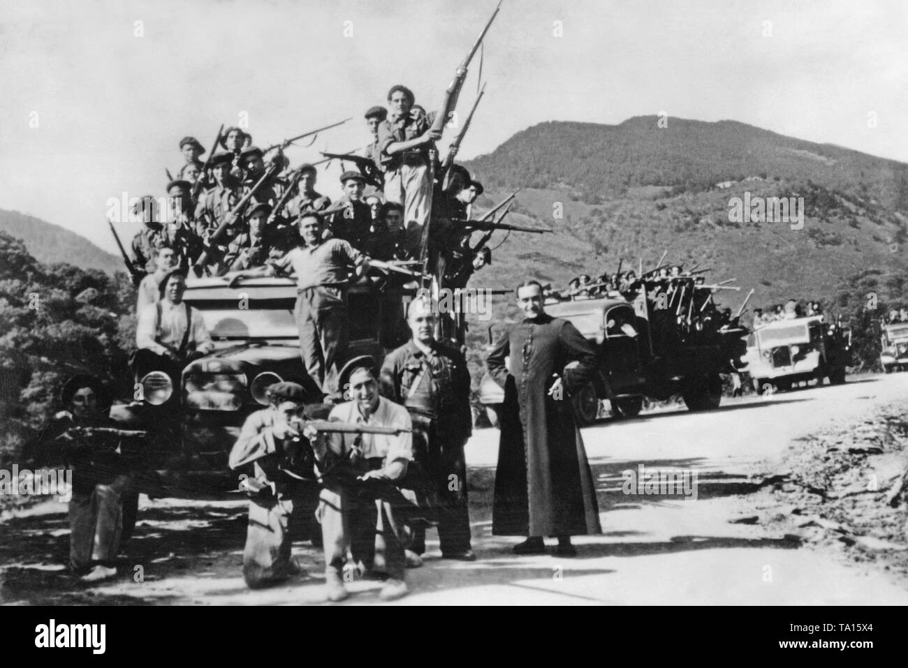 Il generale Franco tifo truppe sono adottate per la parte anteriore sui carrelli a San Sebastian, Paesi Baschi, Spagna. Al centro, un cattolico ecclesiastico locale in nero soutane pone con la truppa che presentano i loro moschettoni. La città spagnola di San Sebastian (24km ad ovest del confine francese) cadde nelle mani di Franco, le truppe. Foto Stock