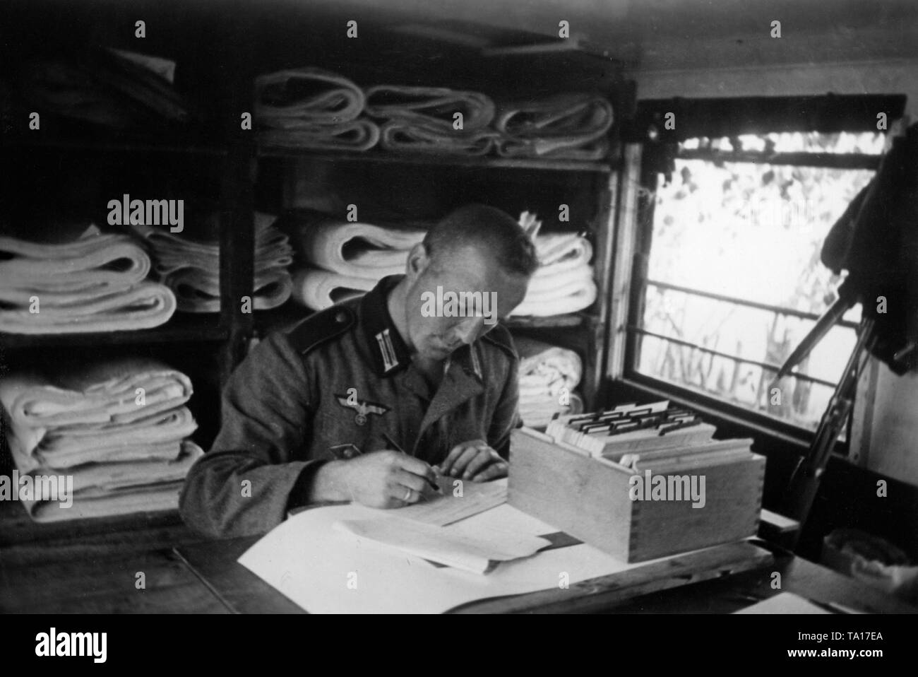 Un membro della Wehrmacht dispone di scorte di mappe e registra le mappe su schede. Foto: reporter di guerra Utecht. Foto Stock