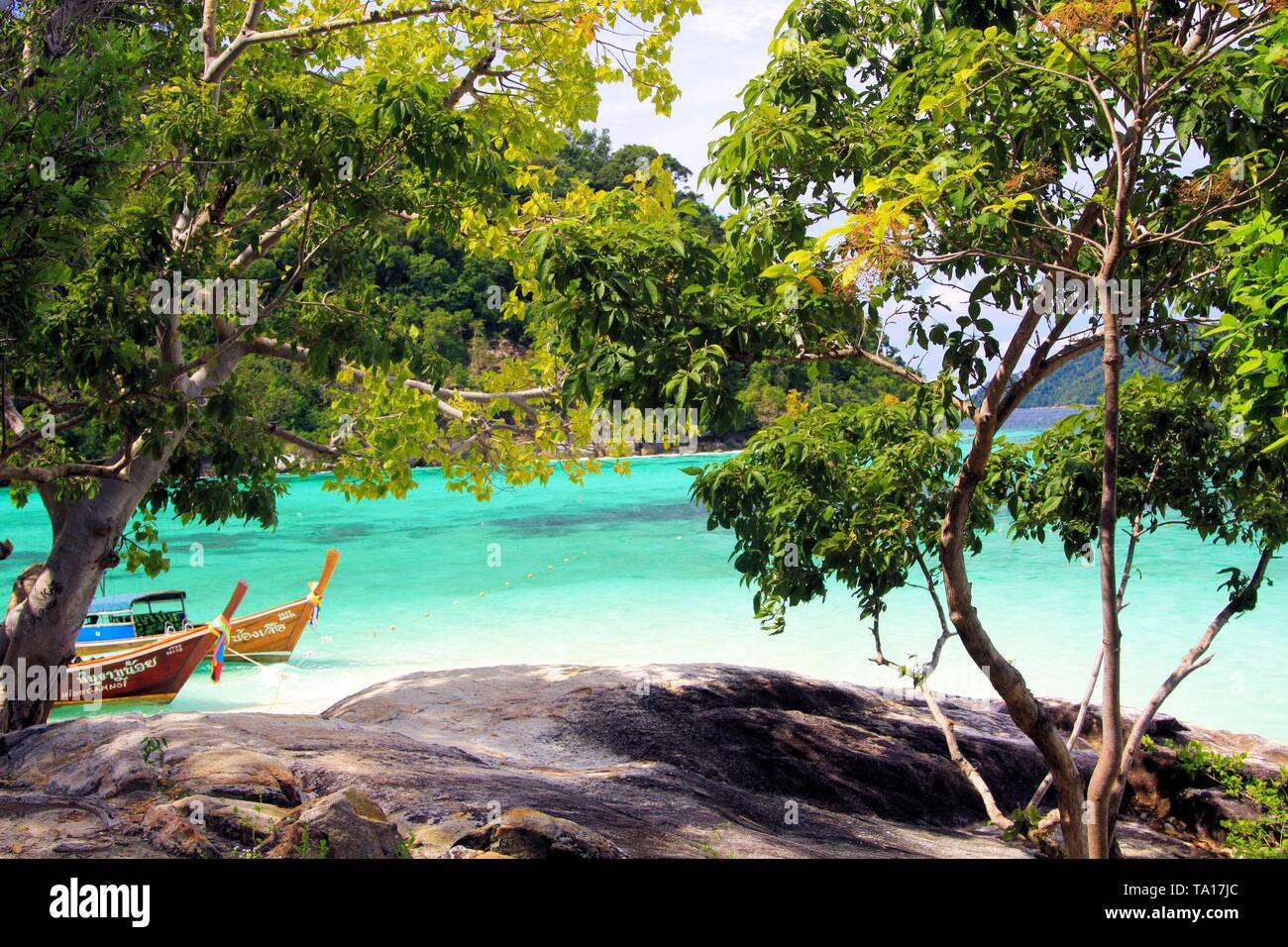 KO MOK, Thailandia (Mare delle Andamane) - Dicembre 28. 2013: la vista al di là di alberi e altopiano roccioso isolato sulla lunga coda di barche e acqua turchese Foto Stock