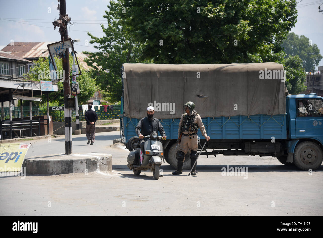 Un uomo del Kashmir visto con uno scooter accanto un veicolo blindato durante le restrizioni in Srinagar. Le autorità impongono delle restrizioni in parti di Srinagar per impedire l 'Eidgah marzo " chiamato dai separatisti. Il mese di marzo è stato chiamato per contrassegnare la morte gli anniversari di Moulvi Muhammad Farooq, Abdul Gani Lone e la Hawal martiri. Foto Stock