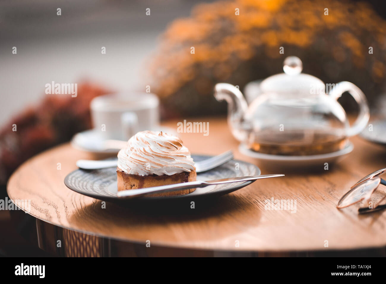 Gustosa torta cremosa sulla piastra con vetro teiera e tazza sul tavolo di legno. Buona mattina. La prima colazione. Foto Stock
