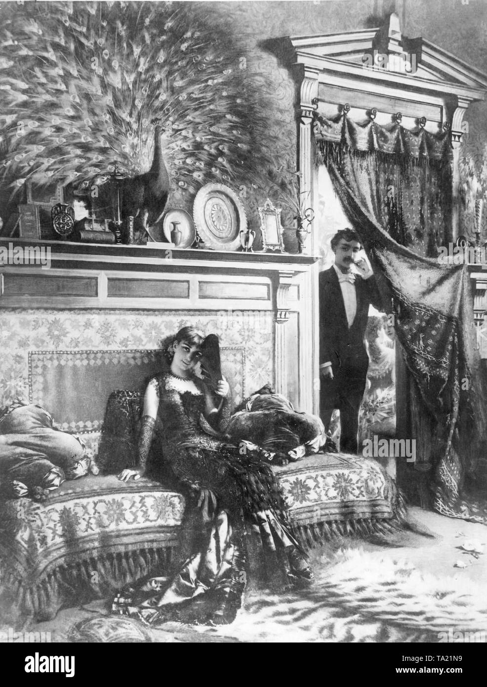 Un giovane uomo con sigaretto entra in una stanza dove una giovane donna seduta su un divano con un ventilatore nella sua mano. Foto Stock