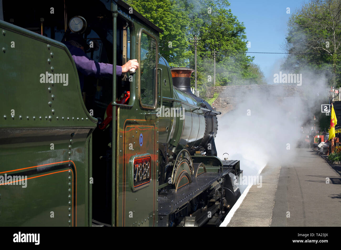 Una locomotiva a vapore lasciando la piattaforma dei Vescovi Lydeard stazione ferroviaria nel Somerset, Regno Unito, con il vapore offuscare il più distante vista. Foto Stock