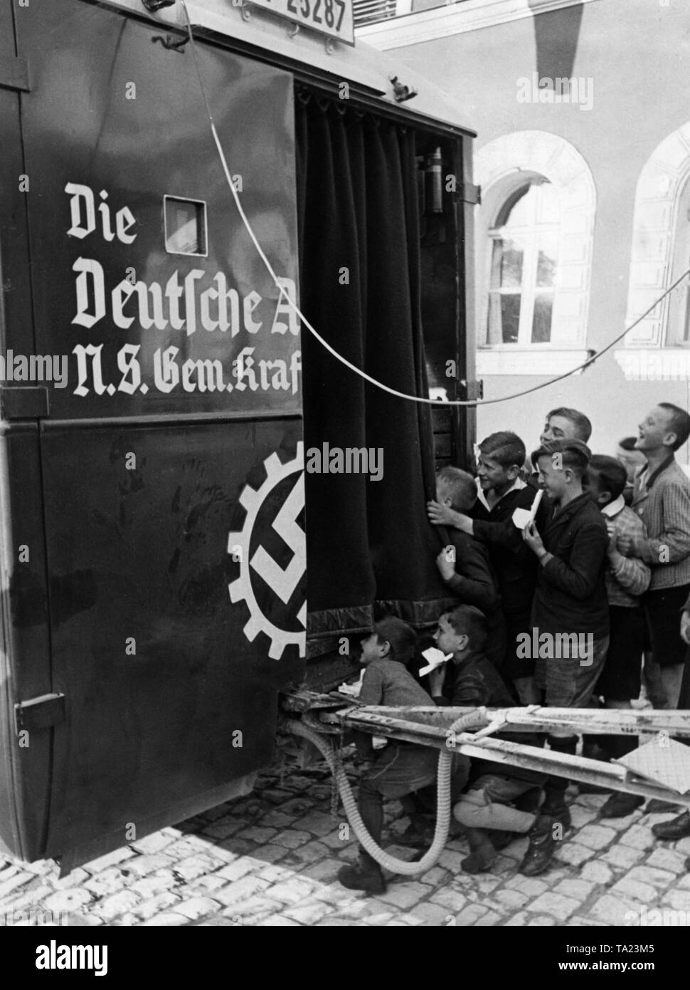 Foto non datata di un teatro auto dell'organizzazione nazista "Kraft durch Freude' ('Sforzo attraverso Gioia") con un built-in proiezione film macchina, curiosi i bambini guardano a. Foto Stock