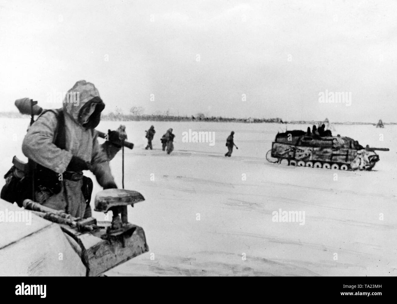 Un tedesco Jagdpanzer IV (serbatoio di caccia), insieme con fanti, anticipi sui campi innevati della Puszta ungherese. Uno degli uomini sulla sinistra sta portando un Panzerfaust.Il tagliare il veicolo è un blindato trasporto di personale Sd. Kfz.251. Cospicuamente, il muso freno della Jagdpanzer è mancante. Questi erano spesso smontati, come hanno suscitato troppa polvere e in questo modo hanno rivelato la propria posizione. Foto Stock