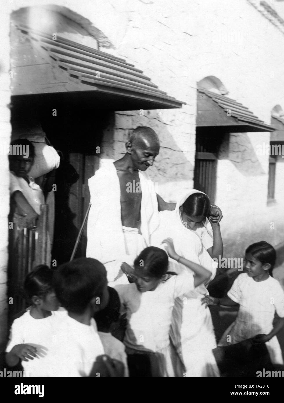 Il leader dell'Indiano movimento di indipendenza, il Mahatma Gandhi, lasciando una scuola. Foto Stock